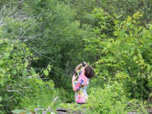 Young person with binoculars looking into a forested area